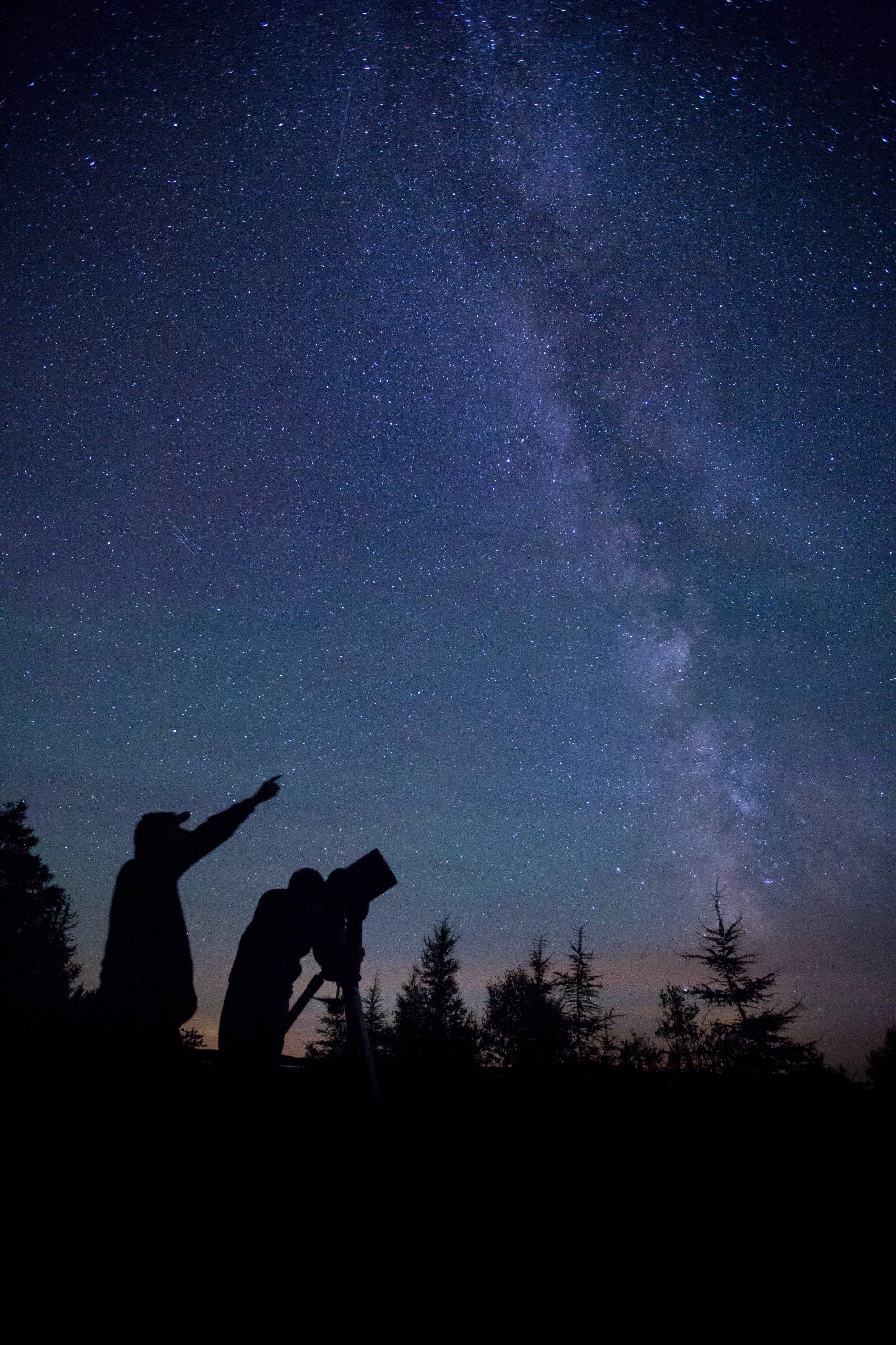 Faculty and students looking at the night sky through a telescope.